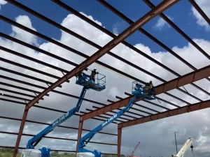 Two workers installing a prefabricated steel building metal structure